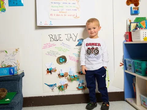 a boy standing in front of a white board with drawings on it