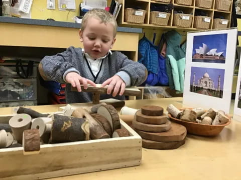 a boy sitting at a table with clay pots and bowls