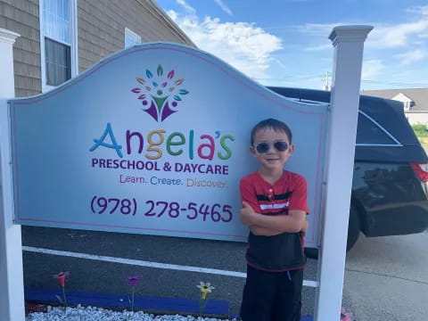 a boy standing in front of a sign