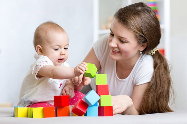 a person and a baby playing with toys