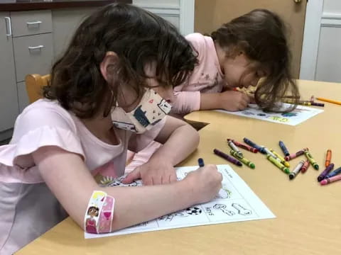 a few young girls coloring on paper