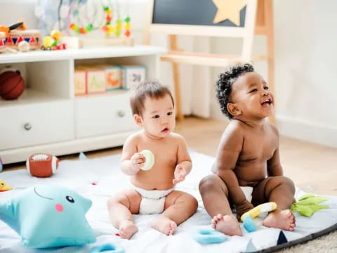 two babies sitting on a bed
