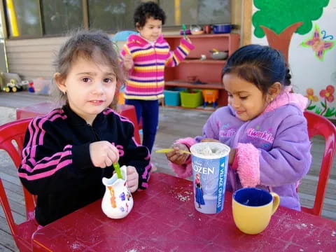 a group of children sitting at a table eating food