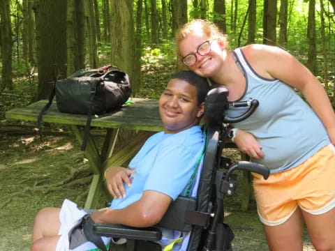 a woman and a boy in a wheelchair in the woods