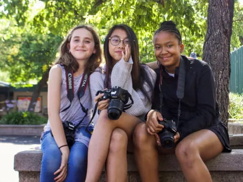 a group of people sitting on a bench holding cameras