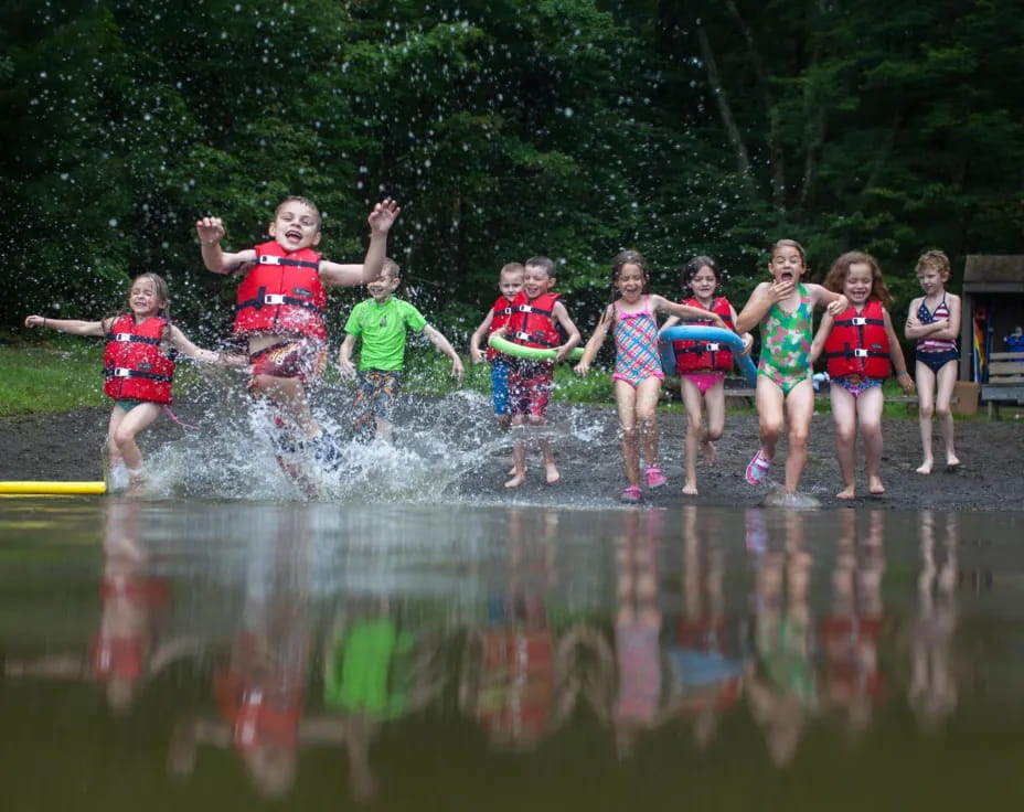 a group of children jumping into a body of water