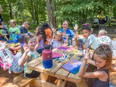 a group of children sitting around a table outside