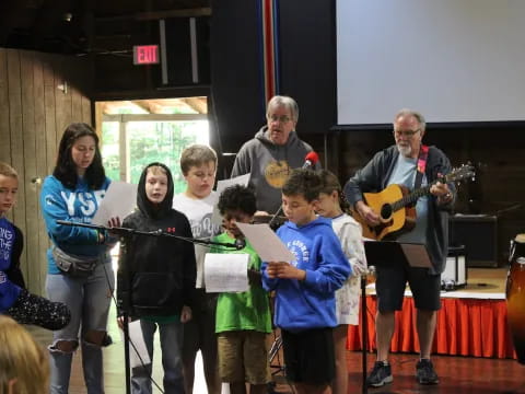 a group of people standing in front of a person playing a guitar