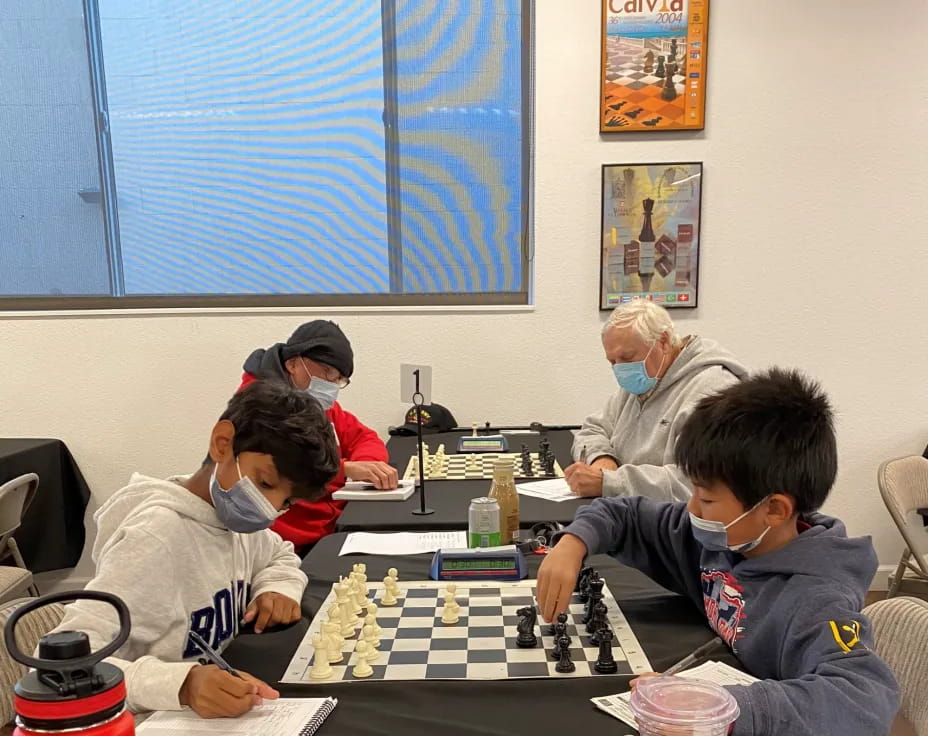 a group of people sitting around a table playing chess