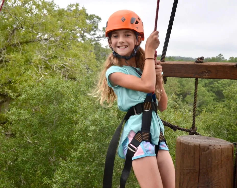 a girl wearing a helmet and climbing a rope