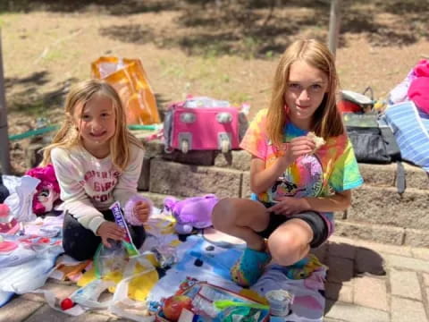 two girls sitting on a blanket