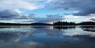 a body of water with trees and mountains in the background