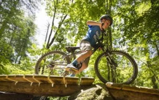 a man riding a bike on a wooden platform in the woods