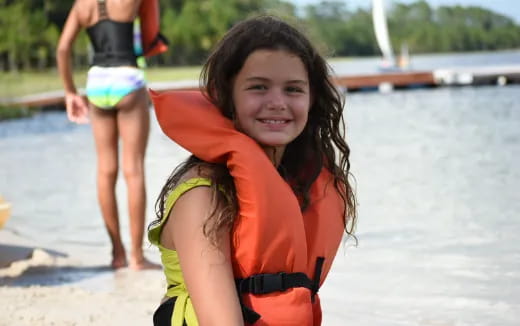 a girl in a life jacket on a beach