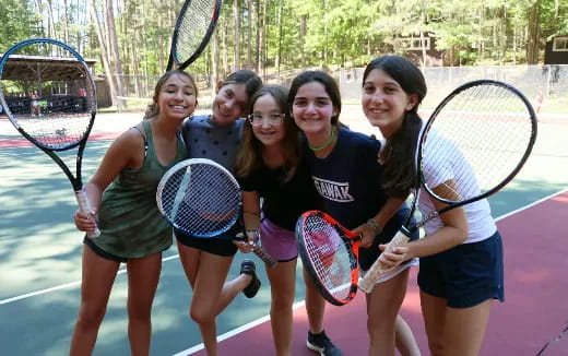a group of girls holding tennis rackets