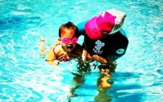 a person and a baby in a pool with a ball