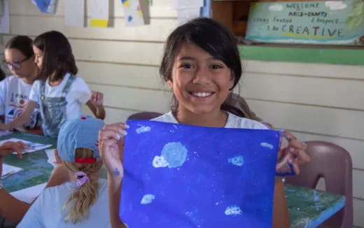 a young girl holding a blue book