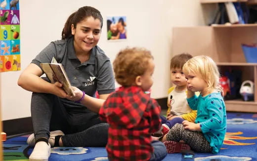 a person reading a book to a few children
