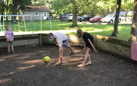 a couple of people playing with a ball in a park