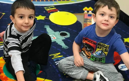 two boys sitting on a mat