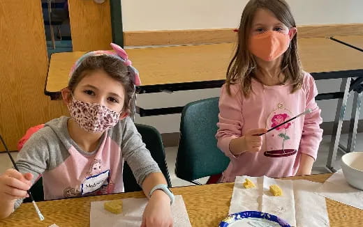 a couple of girls sitting at a table with a cake
