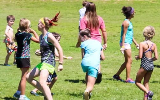 a group of girls running on a grass field