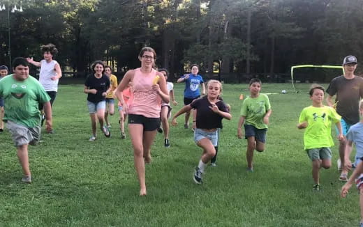 a group of people running on a grass field