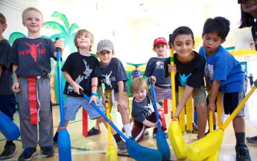 a group of kids holding brooms