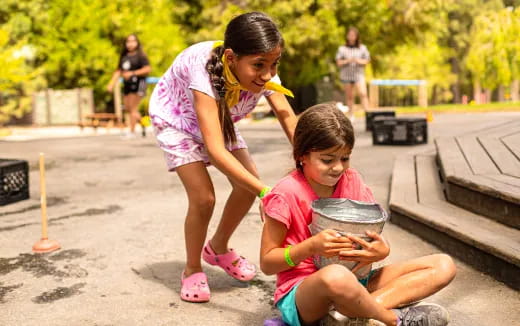 a couple of girls playing with a drum
