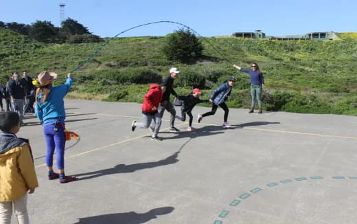 a group of people playing with a rope on a road