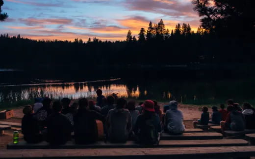 a group of people sitting on a dock looking at a lake