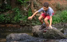 a child jumping over a rock