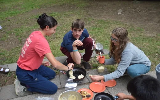 a group of people sitting on the ground eating food