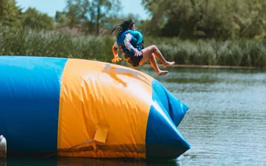 a girl jumping off a slide into a body of water