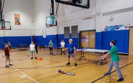 a group of people playing ping pong in a gymnasium