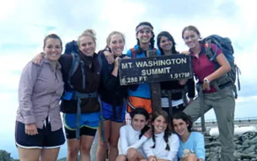 a group of people posing for a photo with a sign