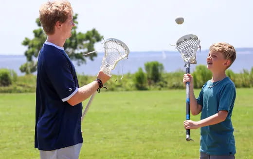 a person and a boy playing lacrosse