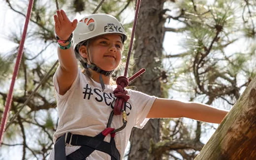 a young boy wearing a helmet and harness on a rope