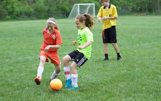 a group of kids compete over a football ball