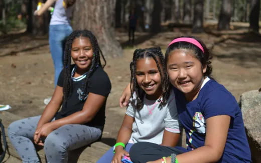 a group of girls sitting on a rock