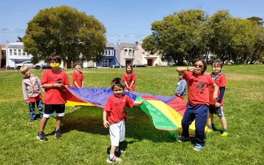 a group of kids running with a kite