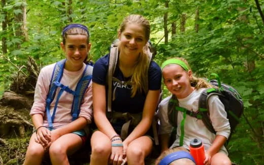 a group of women sitting on a rock in the woods