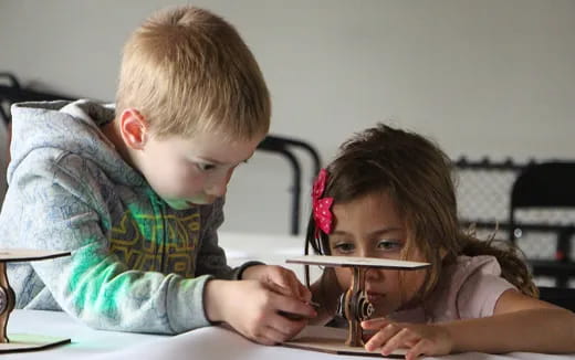 a boy and girl sitting at a table with a spoon