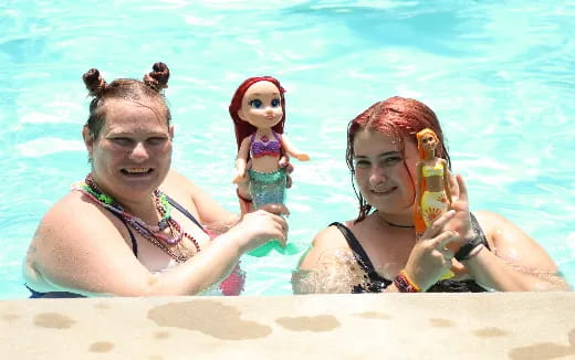 a man and woman in a pool with a doll in a garment