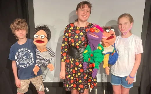 a group of kids posing with a person in a garment