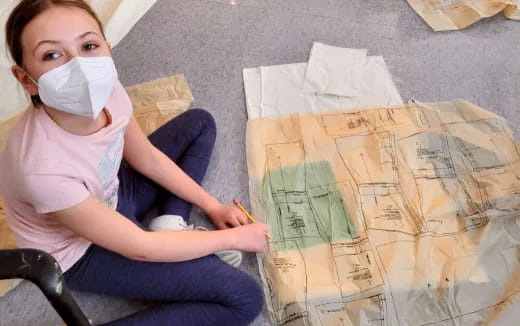 a young girl wearing a mask and holding a pencil