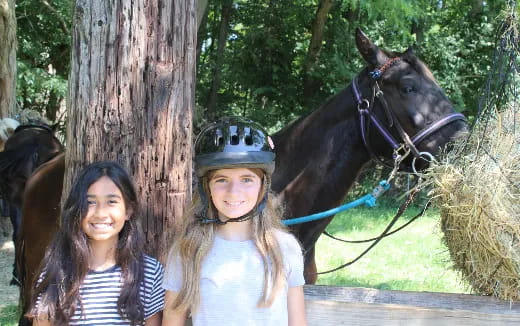 two girls standing next to a horse