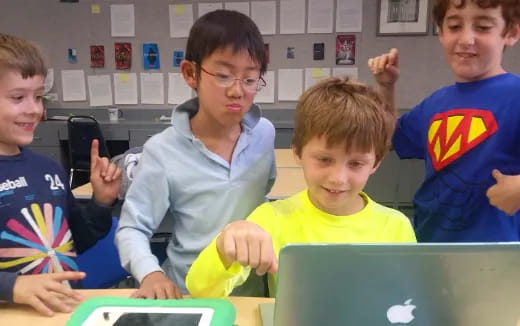 a group of kids looking at a laptop