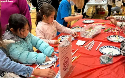 a group of children sitting at a table painting