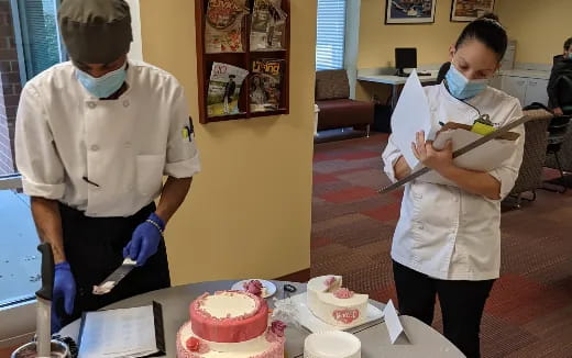 a couple of people cutting a cake